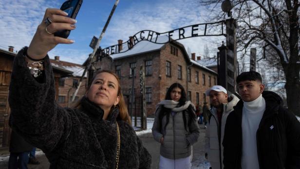 Eine junge Frau steht vor den Toren eines Konzentrationslagers und macht ein Selfie