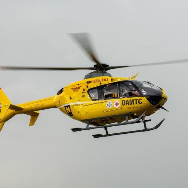 Ein gelber Christophorus Hubschrauber des ÖAMTC fliegt am grauen Himmel.
